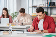 © LIGHTFIELD STUDIOS - Concentrated student sitting at desk and reading book in classroom