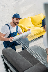 Canvas Print - mover wrapping couch with roll of stretch film in apartment