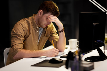 Canvas Print - business, deadline and people concept - man with notepad and computer working late at night office