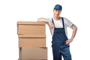 Wall Mural - handsome mover in uniform with cardboard boxes looking at camera isolated on white