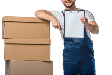 Wall Mural - cropped view of mover in uniform holding blank clipboard near cardboard boxes isolated on white