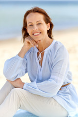 people and leisure concept - portrait of happy smiling woman on summer beach