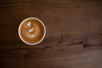 Piccolo Latte art in paper cup on wooden desk