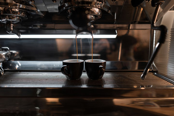 Professional modern espresso coffee machine pours hot drink into the cup. Two vintage cups stands in the coffee machine. Coffee break in a cafe.