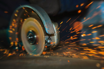 Close-up of the rotation of the angle grinder disc during operation. Artificial blur with shallow depth of field.  Bright sparks from metal cutting