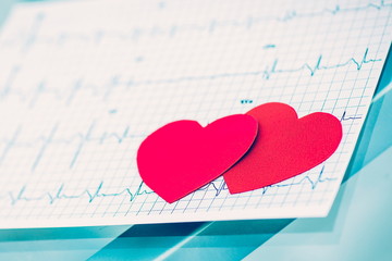  health concept: two red paper heart on the electrocardiogram, the cardiologist.