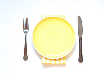 Yellow empty plate concept flat lay with fork and knife. Top view