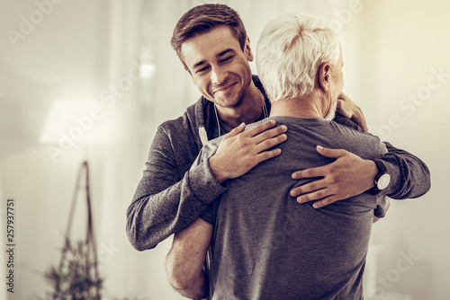 Smiling handsome young man embracing grey-haired dad cheering him up Poster Mural XXL