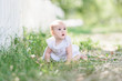 © laniko - baby girl wearing white dress sitting on the grass