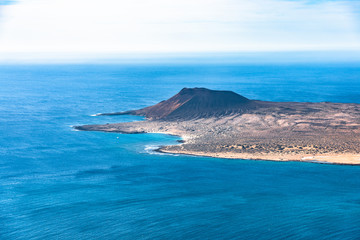 Wall Mural - Unique panoramic magnificent aerial view of volcano cone at volcanic island La Graciosa south coast, in Atlantic ocean, from Mirador del Rio, Lanzarote, Canary Islands, Spain. Travel concept.