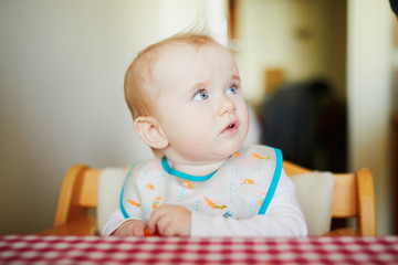 Wall Mural - Cute baby girl eating carrot in the kitchen