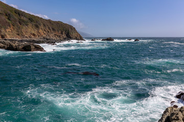 Wall Mural - Long exposure of deep blue water, swirling surf, and rocky cliffs of central California