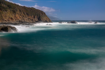 Wall Mural - Long exposure of deep blue water, swirling surf, and rocky cliffs of central California