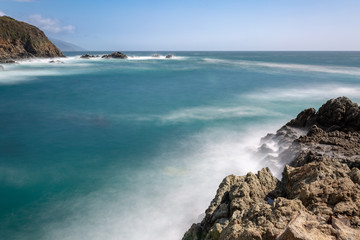 Wall Mural - Long exposure of deep blue water, swirling surf, and rocky cliffs of central California