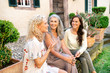 © Westend61 - Three happy women of different age sitting at country house talking