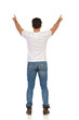 © studioloco - Young Man In Jeans And White T-shirt Is Standing And Showing Something. Rear View