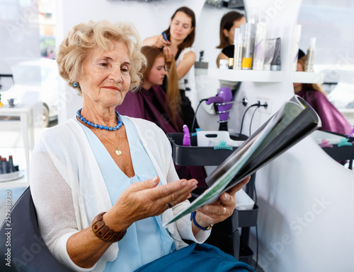 Smiling Elderly Female Client Sitting With Magazine In Chair In
