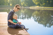 © kieferpix - Family, parenting Happy smiling mother and son sitting on a wooden dock lake side.