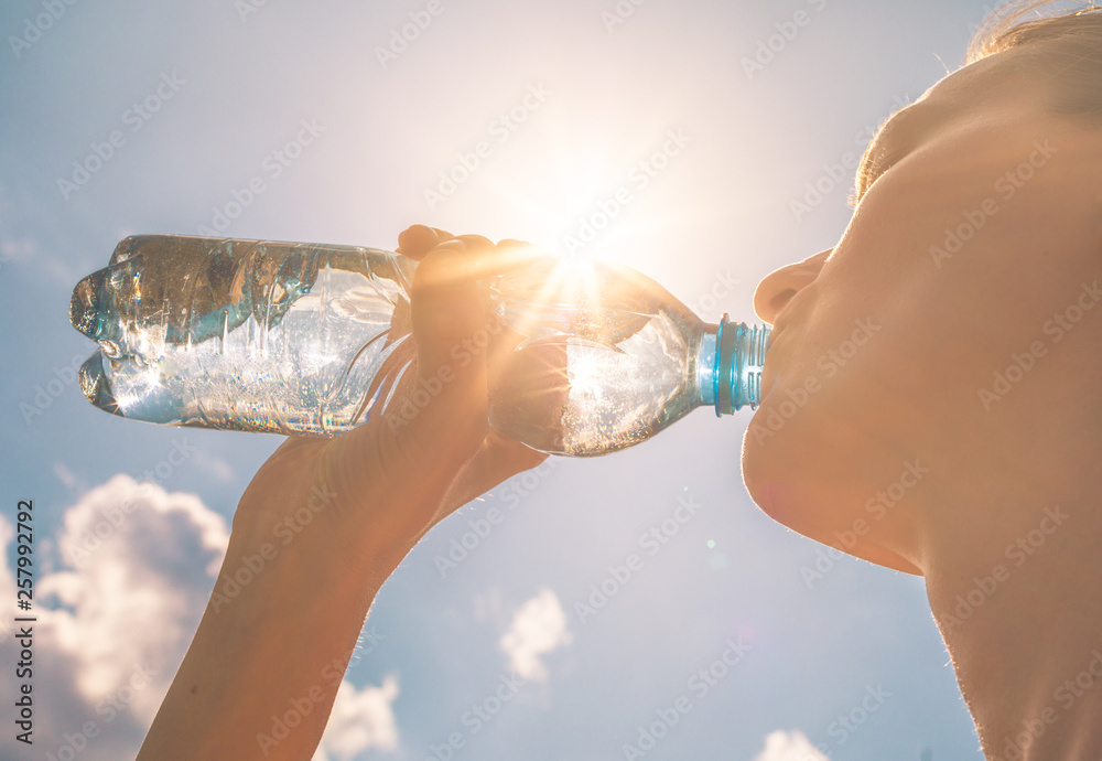Young woman drinking bottle of water - obrazy, fototapety, plakaty 