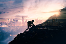 Silhouette Of Man Climbing Up Mountain Overlooking City