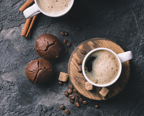 Black fried coffee beans in cafe with cookie and cake on dark textured background