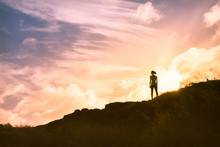 silhouette of woman standing on top of mountain watching the sunset