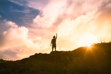 Victory, triumph, silhouette of man on top of mountain at sunset
