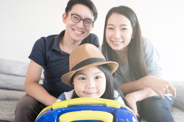 Happy Asian family is preparing for travel at home .Mom daughter and father are packing suitcases for the trip.