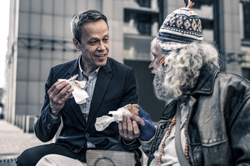 communicative kind man talking to grey-haired senior homeless