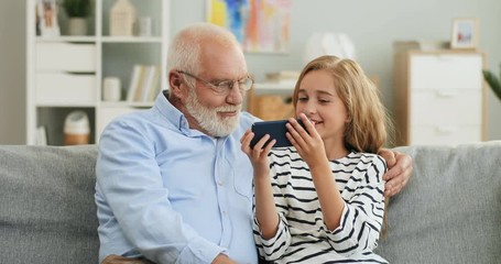 portrait shot of the caucasian grandfather and granddaughter resting on the couch in the living room