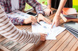 © kittipong - Close-up of  business people brainstorming at office desk. Business man and customer hands pointing at business data on a sheet  while discussing analyzing financial reports .