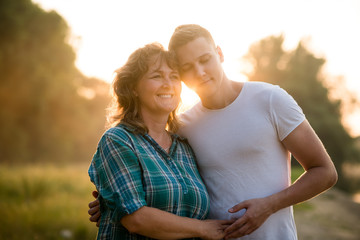 Boy leaning over her mother. Nature background.