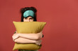Sleepy young woman with mask and pillow on color background