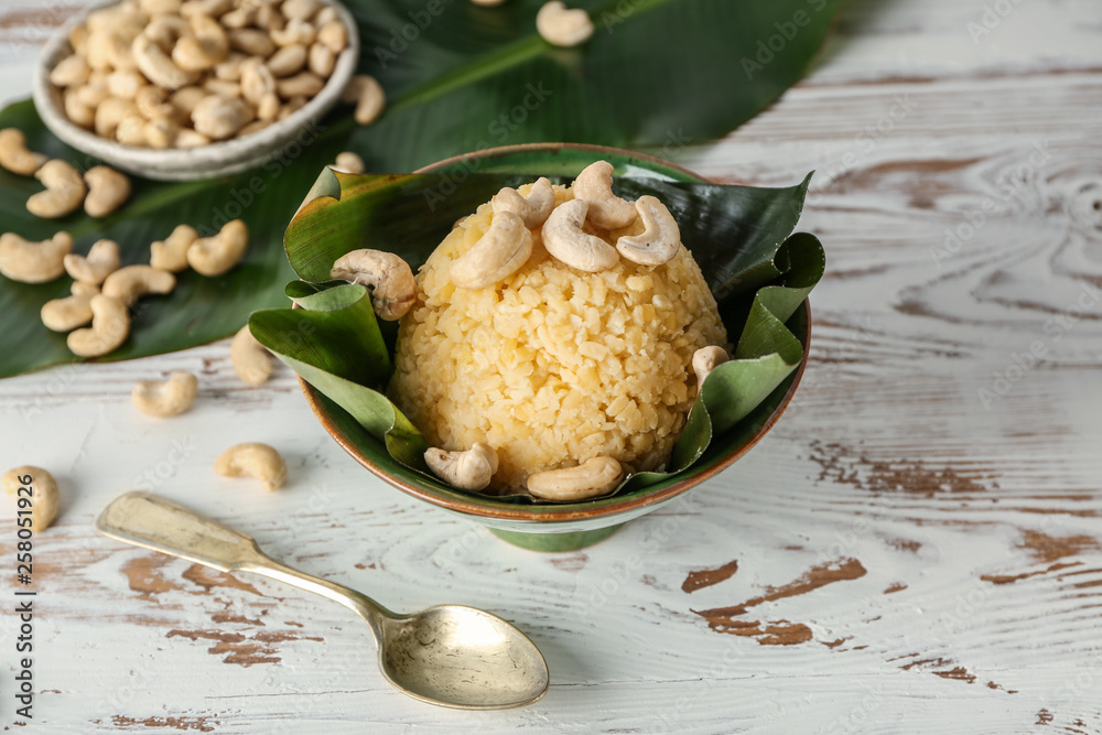Bowl with traditional Indian food pongal on table