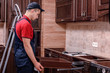 © Ахтем - A young worker installs a drawer. Installation of modern wooden kitchen furniture