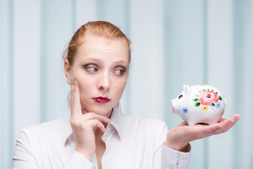 Wall Mural - young red haired woman with her piggy bank