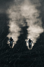 Two Friends Racing On Custom Retro Style Cafe Racer Black Motorcycles On The Black Lava Sand At Sunrise On Mount Batur, Bali, Indonesia
