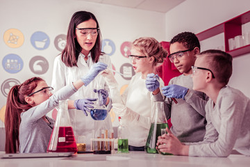 Young scientists helping their teacher with reagents