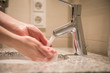 Frau nutzt Waschbecken mit Wasserhahn und Leitungswasser zum Händewaschen