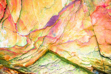 Wall Mural - Multicolored rock wall from bottom sediments red orange dark rays crack smooth