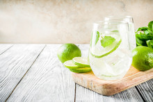 Summer Sour Drink, With Lime And Mint, Homemade Cocktail Mojito In Two Glasses, White Wooden Background, With Fresh Limes, Mint Leaves, Ice Cubes, Copy Space