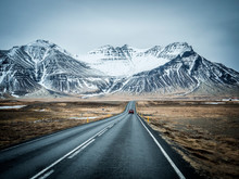 Modern Car Riding On Asphalt Countryside Road Towards Magnificent Snowy Mountains During Trip Through Iceland