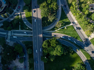 Highway crossroads in Rio de Janeiro seen from above. Aerial view of transit in green urban environment at sunrise.