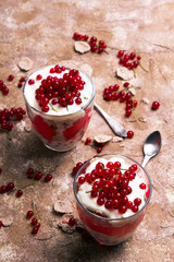 Wall Mural - Healthy dessert with organic red currants, fresh yogurt and corn flakes. Dietary breakfast on a brown background