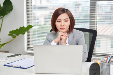 Casual businesswoman thinking about possibility of seeking new business opportunities. Minimalist design. Wooden table. Comfortable workplace with a laptop