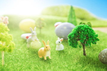 Rabbit toys with easter eggs on a meadow grass. Yellow easter egg spring meadow with two rabbit and easter eggs. Fairy tale