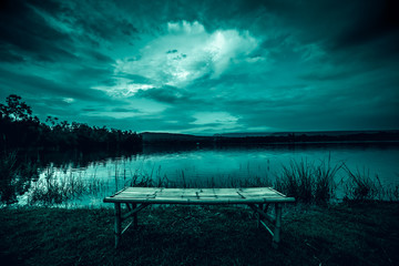 Wall Mural - bamboo litter on grass in front of lake and moonlight behind a cloudy at night time