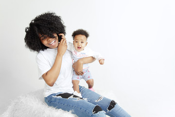 Closeup portrait of beautiful african woman holding on hands her little daughter on white background. Family, love, lifestyle, motherhood and tender moments concepts. Mother's day concept or