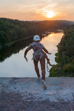 Girl Jumping From The Bridge. A Girl With An Incredible Time Is Engaged In Freestyle In Bungee Jumping. A Young Girl Performs A Reverse Trick In Bungee Jumping. Jump At Sunset Extreme Young.