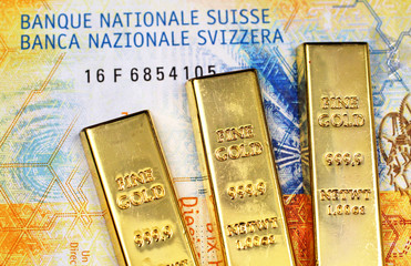 Wall Mural - A close up image of a ten Swiss Franc bank note with three small gold bars in macro